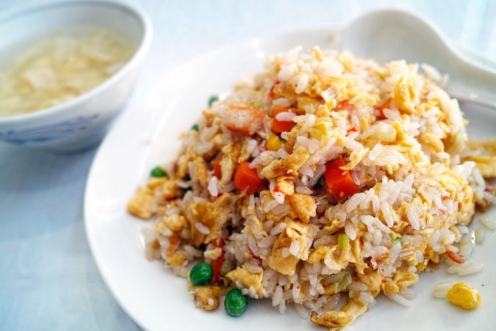 Fried rice with egg, peas and carrots on a white plate