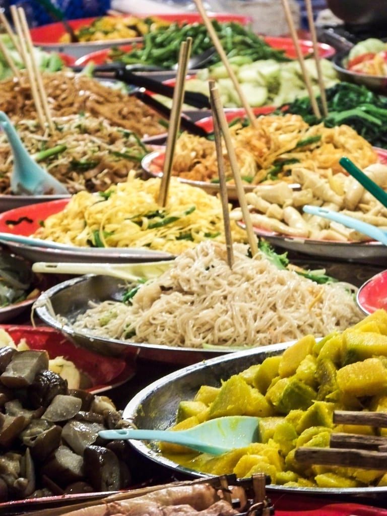 Trays of stir-fried noodles and dumplings with chopsticks